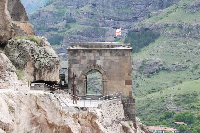 Arche en pierre et chemins dans la falaise à Vardzia, avec la vallée au-delà.