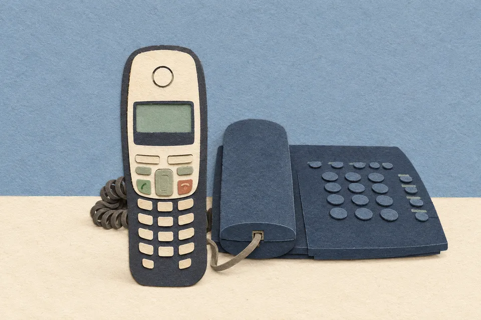 Bezdrátové telefonní sluchátko a základna na stole.