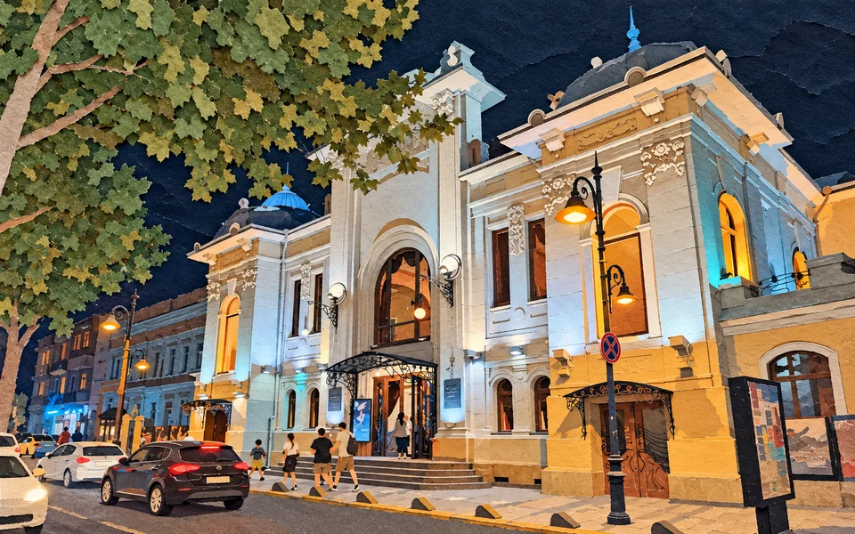 Noční osvětlené divadlo Marjanishvili v Tbilisi, před nímž projíždějí auta a procházejí chodci.